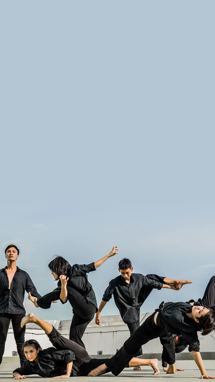 Stylized image with blue and purple gradient overlay of
	six dancers dressed in all black performing an interpretive dance.